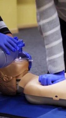 Dummies for medics used for first aid training. Experienced unrecognizible doctor gives recommendations. Oxygen mask on medical doll. Vertical video