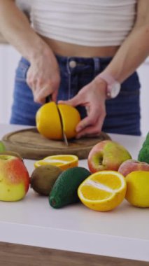 Woman cutting fruit in the kitchen. Beautiful young woman preparing fruit salad in kitchen Vertical video