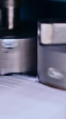 İki metal silindir dönüyor ve gelecekteki bebek bezleri için dokuyu itiyor. Beyaz bez parçaları konveyör hattındaki bir yığının içine konmuş. Bebek bezi imalatı yakında. Dikey video