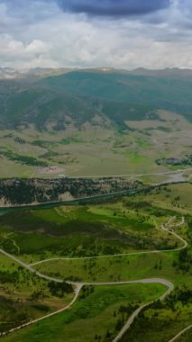 Dağlık bölgedeki nehirlerin yakınındaki inanılmaz güzel yeşil vadiler. Colorado 'da dağın eteğindeki küçük bir kasaba. Arka planda, dağ sırasının üzerinde dramatik bir gökyüzü. Dikey video