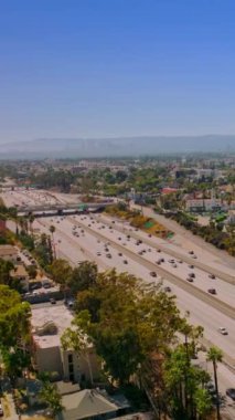 Arabaları Los Angeles, California, ABD 'deki çok şeritli otoyollara süratle taşıdı. Arka planda inanılmaz açık mavi gökyüzü. İHA görüntüleri yükseliyor. Dikey video
