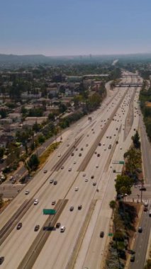 Çok şeritli otoban, büyük şehirden geçen sayısız araba. Los Angeles 'ın güneşli görüntüsü. Dikey video