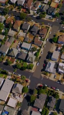Los Angeles, California, ABD 'deki yerleşim bölgesi manzarası. Güneşli bir günde özel evlerin çatılarında uçmak. Hava görüntüsü. Dikey video