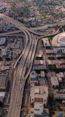 Los Angeles, California, ABD 'deki çok şeritli otoyollarda büyük kavşaklar. Çılgın trafiği olan inanılmaz bir şehir manzarası. Hava görüntüsü. Dikey video