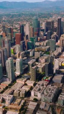 Gökdelenler ve Los Angeles 'ın çok katlı binaları. Dağların arka planında çarpıcı şehir manzarası. Dikey video