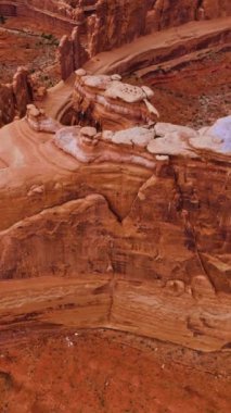 Utah, ABD 'deki Arches Ulusal Parkı' ndaki göz kamaştırıcı duvar taşlarının üzerine iniyor. Gündüz kanyonların inanılmaz manzarası. Hava görüntüsü. Dikey video