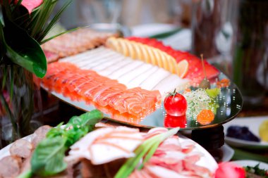 Çeşitli suşi ve diğer yiyeceklerle dolu bir masa. Suşi öyle bir düzenlenmiş ki aynaya benziyor.