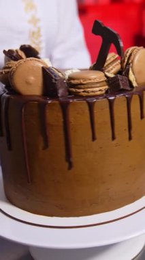 Pasta aşçısı kürsüde güzel çikolatalı pasta yapıyor. Şekerlemecide üretilen hazır tatlı ürünü. Kapatın. Dikey video