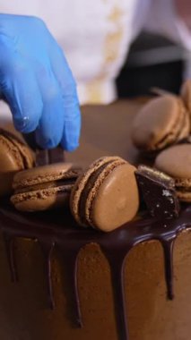 Gıda fabrikasında çok güzel dekore edilmiş çikolatalı pasta. Pastacılar tatlıları büyük pastanın üstüne koyarlar. Kapatın. Dikey video