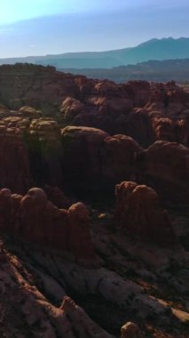 Utah, ABD 'de parlak güneş ışınlarıyla yuvarlak kırmızı kayalar. Arches Ulusal Parkı mavi gökyüzünün arka planında. Hava görüntüsü. Dikey video