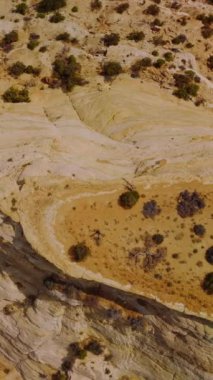 Utah Ulusal Parkı 'ndaki terk edilmiş bölgelerin kurak ve cansız manzarası. Parlak sıcak güneşle aydınlatılmış kayanın üzerindeki drone görüntülerini çember yapın. Dikey video