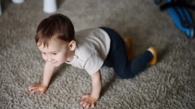 Tapılası melek bebek yerde oturup yukarı bakıyor. Çocuk ayağa kalkıyor ve kameraya doğru geliyor. Kapat..