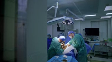 Deneyimli cerrahlar yayan ameliyat yaparlar. Kapıdaki pencereden modern bir ameliyathaneye bak..