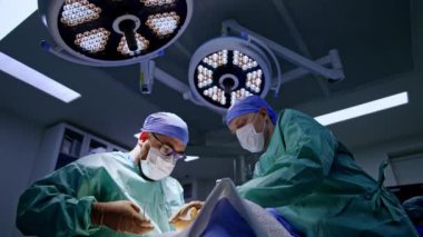 Doktorlar modern ameliyathanede yayan olarak cerrahi prosedürde işbirliği yapıyorlar. Düşük açı görünümü.