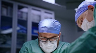 Konsantre cerrahlar ameliyathanede ameliyat yaparlar. Maskeli tıbbi profesyonellerin portrelerini kapatın. Düşük açı görünümü.