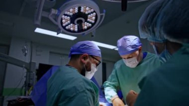 Operasyonel tiyatroda çalışan cerrahi ekip. Doktor ayağında sünger kullanıyor. İlaç uyguluyor..