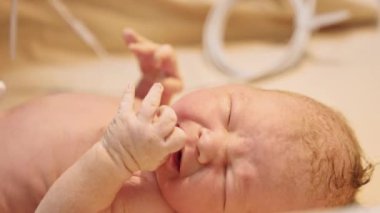 Masada ağlayan yeni doğmuş bebek. Lateks eldivenli doktor teli bir çocuğun eline bağlıyor. Kapat..