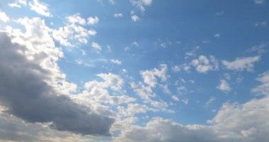 Ufukta parlak beyaz bulutlar uçuşan güneşli mavi gökyüzü. Büyük gri bulut yaklaşıyor ve gökyüzünü kaplıyor. Zaman Uygulaması.