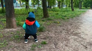 Küçük bebek yerden bir top almak istiyor. Mutlu çocuk kameraya gülümser ve uzaklaşır..