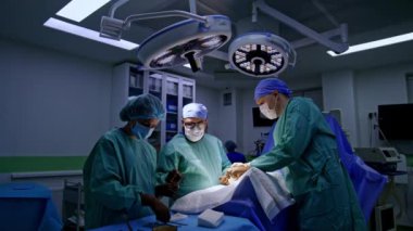 Modern ameliyathanede cerrahi ekip çalışıyor. Profesyonel doktorlar ameliyatı yürüyerek yaparlar. Bayan hemşire asistanı..