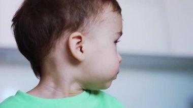 Tatlı erkek bebek yulaf lapası yiyor. Çocuk elinde çatal tutuyor ama annesi kaşıkla besliyor. Kapatın. Bulanık arkaplan.