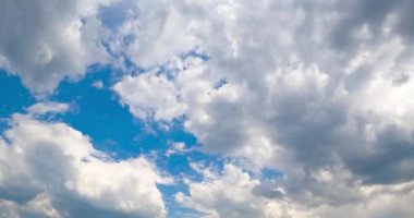 Mavi gökyüzünde süzülen beyaz pamuk bulutları. Küçük bulutlar büyük bir bulutun içinde toplanıyor. Zaman Uygulaması.