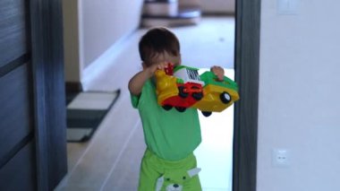 Küçük çocuk oyuncak treniyle oynuyor. Bebek koltuğa koyuyor ama araç hareket etmiyor. Yüksek açı görünümü.