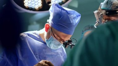 Cihaz gözlüklü nöroşirürji uzmanları hastanın yanında duruyor. Doktorlar çalışırken metal aletler kullanırlar..