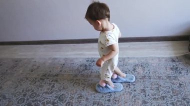 Mavi pofuduk terlik giyen sevimli küçük çocuk odanın bir ucundan diğerine geçiyor. Çocuk annesinin ayakkabılarını ödünç almış..