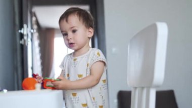 Sevimli küçük çocuk renkli kareleri tutuyor. Bebek evde masanın yanında oyuncaklarla oynuyor..