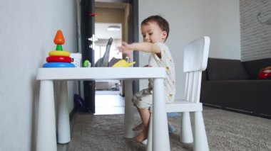 Tatlı beyaz bir erkek bebek masada oturuyor. Sevimli çocuk oyuncak hayvanlarla oynuyor. Düşük açı görünümü.