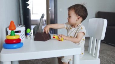 Küçük masada oynayan mutlu, aktif bir çocuk. Çocuk plastik kuşu alır ve masaya vurur..