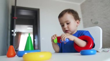 Mutlu küçük çocuk renkli oyuncaklarla neşeyle oynuyor. Çocuk aynı anda birkaç farklı oyuncakla meşgul..