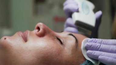 Ultrasonik yüz temizleyicisi kadın yüzünden etkilenir. Kozmetik uzmanı süngeri temizlemek için kullanıyor. Kapat..