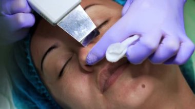 Beyaz kadın cilt bakımı yaptırıyor. Güzellik uzmanı burun gözeneklerini temizlemek için ultrasonik fırça kullanır. Çok yakın çekim..