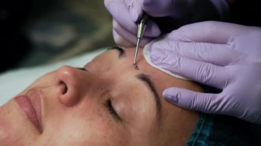 Kozmetoloji uzmanı cilt temizleme işleminde siyah başlık sökme aracı kullanır. Güzellik salonu cilt bakımı. Çok yakın çekim..