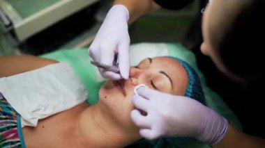 Güzellik salonunda porno temizliği. Beyaz kadın, kozmetik aletinin yardımıyla siyah başlıkları çıkarma prosedürünü uyguluyor. Üst görünüm.