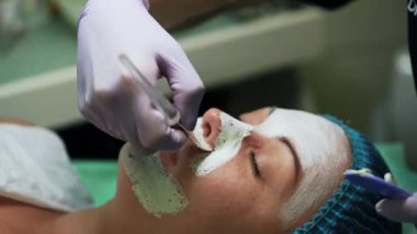 Beyaz maskeli beyaz bir kadının yüzünü kapatıyordu. Güzellik salonunda kozmetoloji prosedürleri. Kapat..