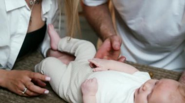 Tanınmayan beyaz anne ve babalar, ekose üzerinde yatan bebeğin yanında dururlar. Anne ve baba çocuklarını okşuyor..