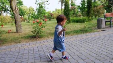 Parkta koşan sevimli çocuğu takip ediyorum. Kot pantolonlu bebek el ele koşuyor..