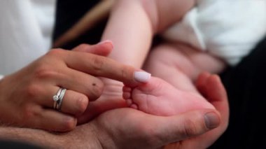 Yetişkinlerin elleri yeni doğmuş şirin bebeklerin ayaklarına dokunuyor. Mutlu annenin küçük bebek parmaklarını okşayan parmağı. Kapat..