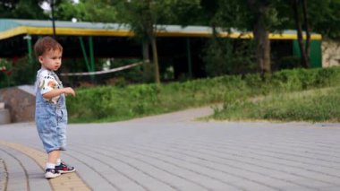 Küçük çocuk dışarıda durmuş asfalt yolda yürüyen güvercini izliyor. Mutlu bebek yaz parkında koşuyor..