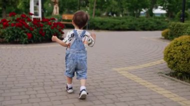 Beyaz çocuk parkta sabun köpüğüyle oynuyor. Gülümseyen bebek yavaşça kabarcıkları yakalıyor..