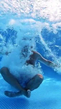 Adam yoga pozisyonunda havuzun berrak sularına atlıyor. Sualtı kamerası suya atlayan bir adamın videosunu çekiyor. Erkek, parmaklarını suyun altına sokarak evet diyor. Dikey video