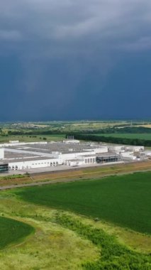 Modern endüstriyel kompleksin geniş bir alanı. Doğayla çevrili büyük bir fabrika arazisinin havadan görüntüsü. Kamera alttan yukarı hareket ediyor. Dikey video