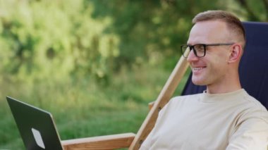 Beyaz adamın doğada dizüstü bilgisayarda çalıştığına eminim. Gözlüklü adam rahatlatıcı bir atmosferde çalışır..