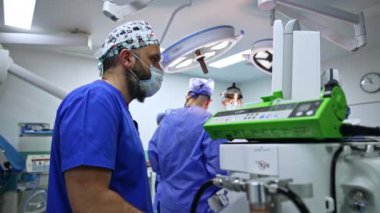 İlgili anestezi uzmanı tıbbi ekipman monitörlerine bakıyor. Hastanın durumunu kontrol eden odaklanmış bir doktor. Düşük açı görünümü.