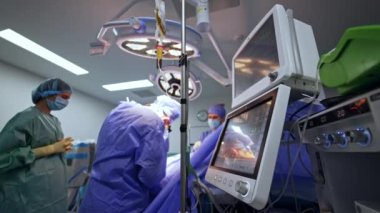 Modern cerrahi odasındaki tıbbi ekipmanlar ameliyat sırasında çalışıyor. Akciğer havalandırma makinesinin monitörlerinde bir hastanın yaşam belirtileri görülüyor..