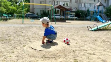 Kot pantolon ve şapka giyen bir yaşındaki çocuk oyun parkında. Bebek yere değdi..