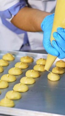 Şekerci, koux hamur işini bir torbadan fırın tepsisine sıkıştırıyor. Hamur fırında pişirmeye hazır olmak. Kapatın. Dikey video
